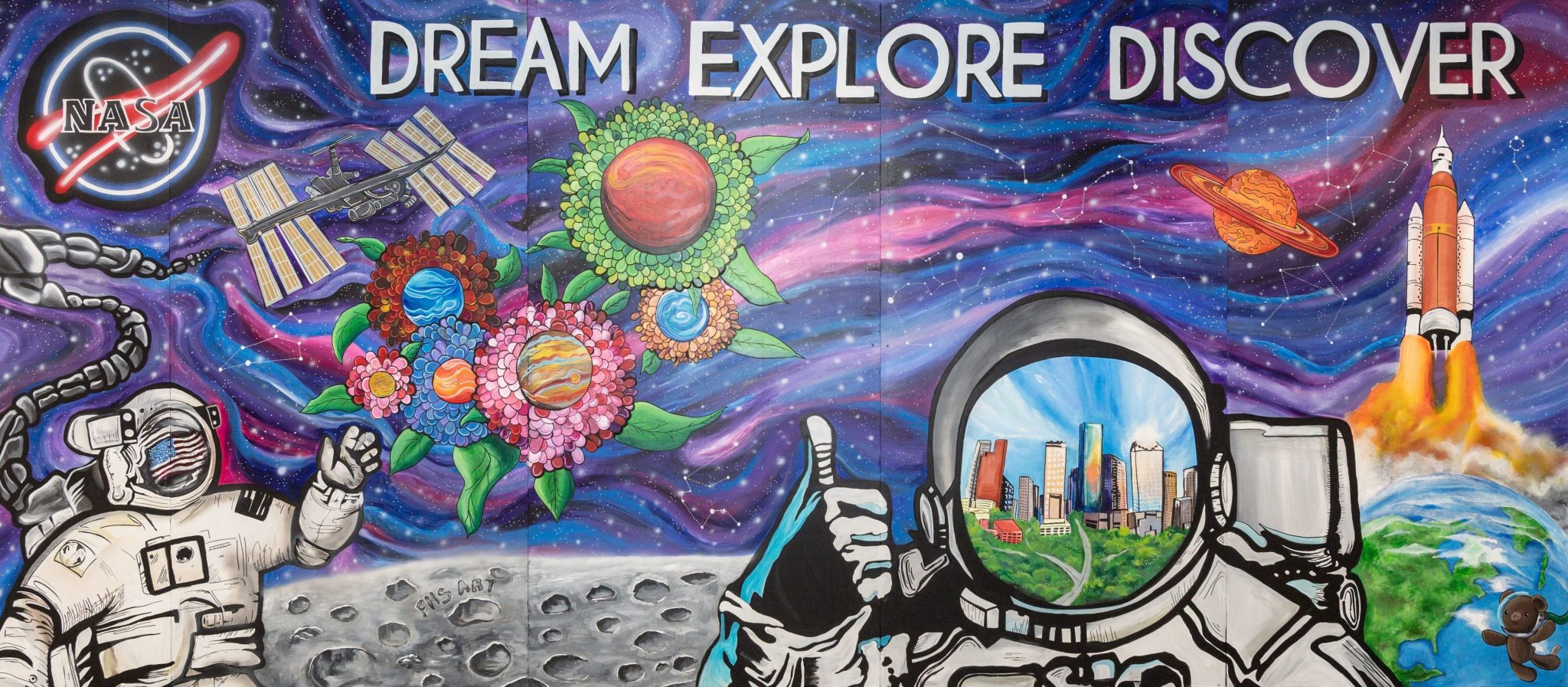 A colorful art mural featuring two astronauts on a lunar landscape with the Dünya and a rocket in the background. The NASA meatball insignia is in the top left corner.